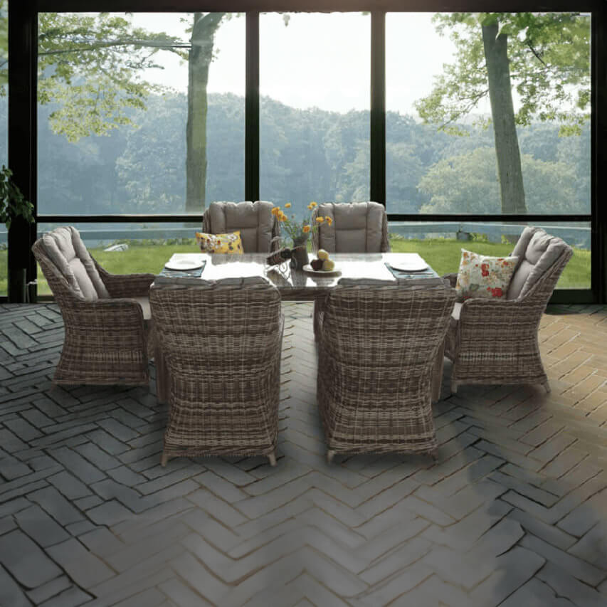 Σετ τραπεζαρίας 6 θέσεων Lefkada από καφέ ρατάν: τραπέζι με γυάλινη επιφάνεια και πολυθρόνες με ψηλή πλάτη και σκούра γκρι καπιτονέ μαξιλάρια, σε ηλιακόλουστο δωμάτιο με θέα στον κήπο.
| Lux Furniture