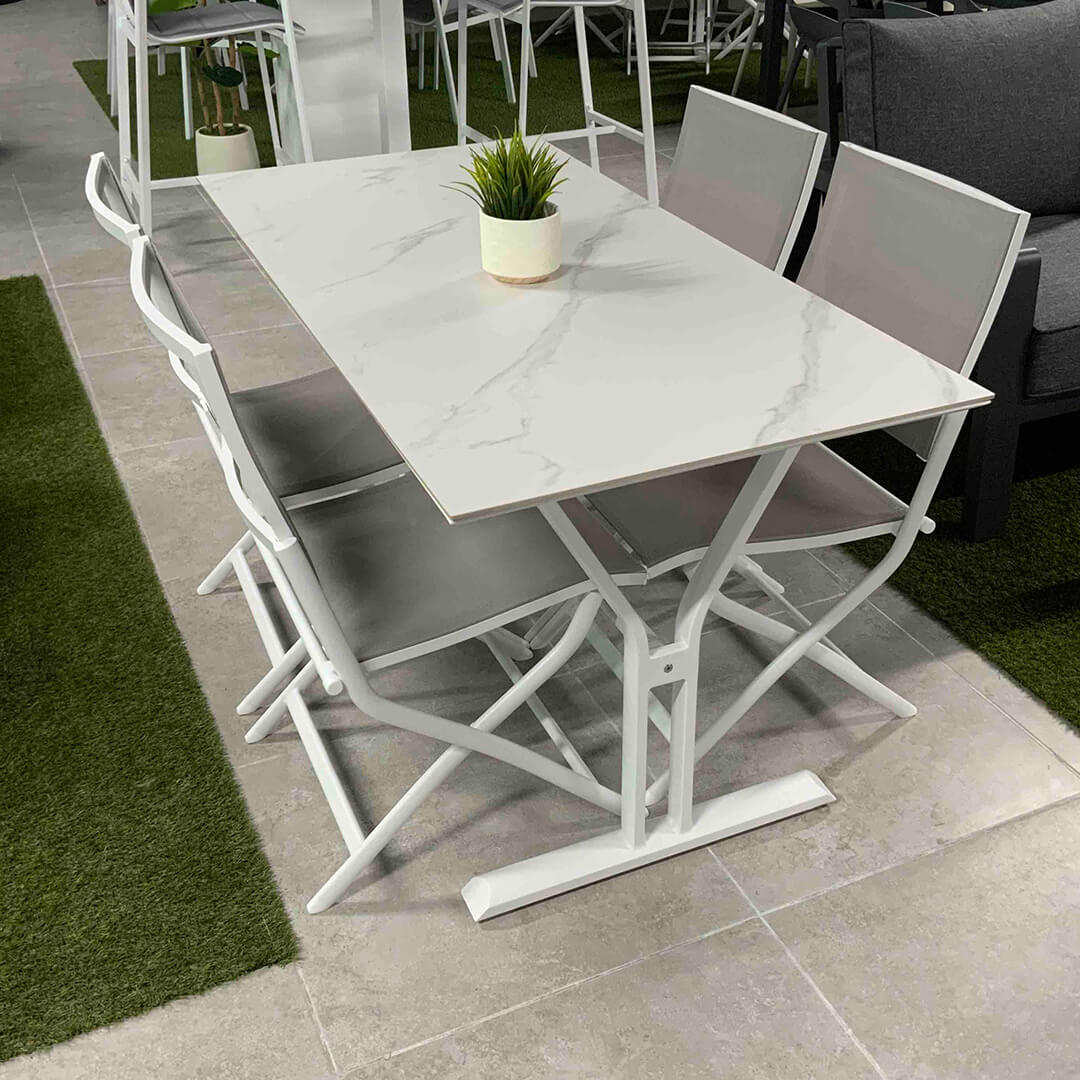 Σετ τραπεζαρίας εξωτερικού χώρου Tiffany, που περιλαμβάνει το ορθογώνιο τραπέζι Sintered Stone και τέσσερις πτυσσόμενες καρέκλες αλουμινίου, σε εκθεσιακό χώρο.