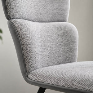 Close-up of the VITRA chair showing the light grey textured fabric, the dark piping and the upholstered back.